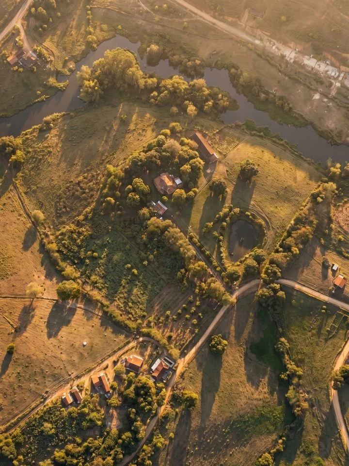 Vista aérea do sítio ao entardecer, com o Rio Jequiriçá contornando a propriedade