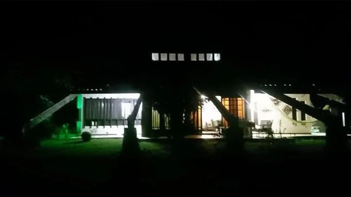 A casa-sede iluminada à noite, vista do gramado